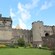 Gente de pie ante el Castillo de Stirling, con muros de piedra, flores y césped